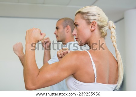 Side view of a sporty young couple clenching fists at fitness studio