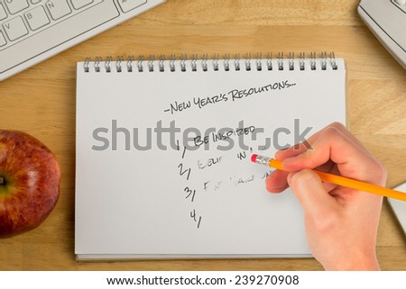 Composite image of new years resolutions against overhead of notepad and technology