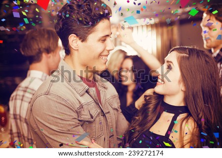 Stylish couple smiling and dancing together against flying colours