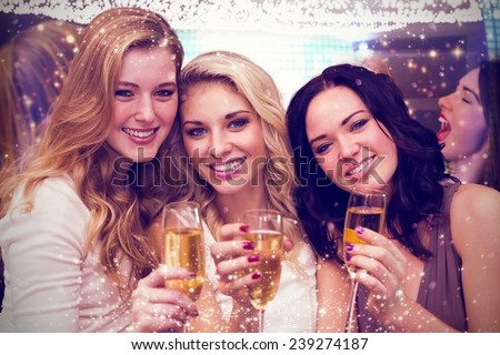 Pretty friends drinking champagne together against gold and red lights