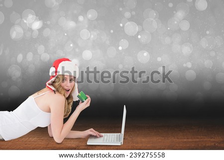 Happy woman shopping online lying on the floor against shimmering light design over boards