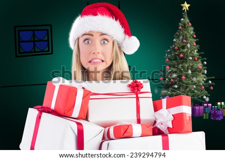 Festive blonde holding pile of gifts against green background with vignette