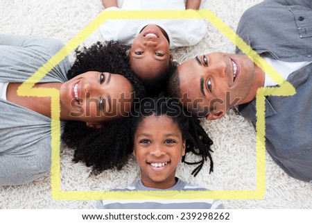 Smiling young family lying on floor against house outline