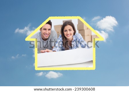 Portrait of a couple lying on the floor and holding a house plan against cloudy sky