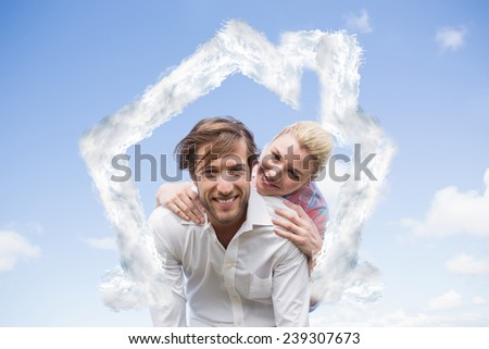 Handsome man giving piggy back to his girlfriend against house outline in clouds