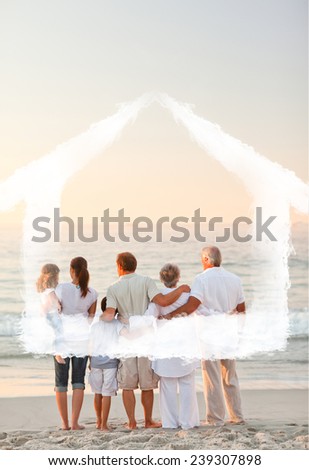 Beautiful family at the beach against house outline in clouds
