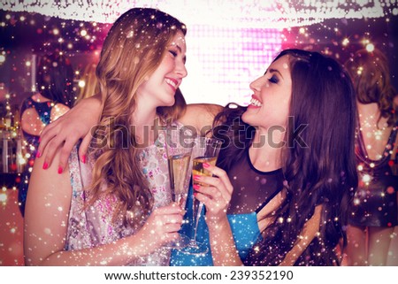 Friends drinking champagne against gold and red lights