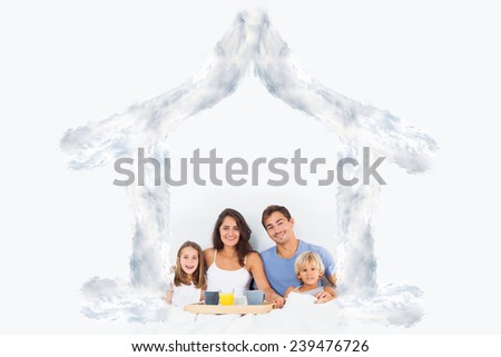 Family taking the breakfast on the bed against house outline in clouds