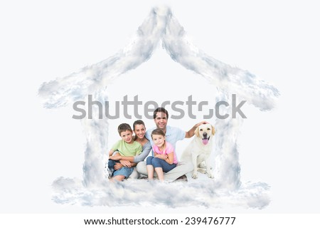 Cute family with pet labrador posing and smiling at camera together against house outline in clouds