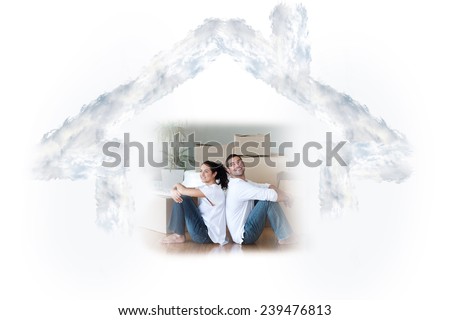 Glowing couple sitting on the floor against house outline in clouds