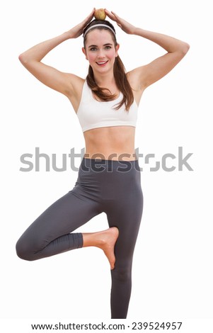 Fit brunette balancing apple on head on white background