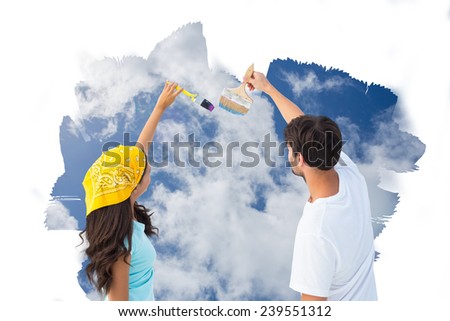 Happy young couple painting together against bright blue sky with clouds