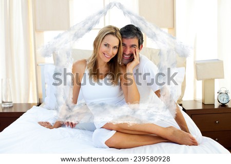 Portrait of lovers sitting on bed against house outline in clouds