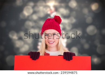 Festive blonde showing a red poster against shimmering christmas tree of lights