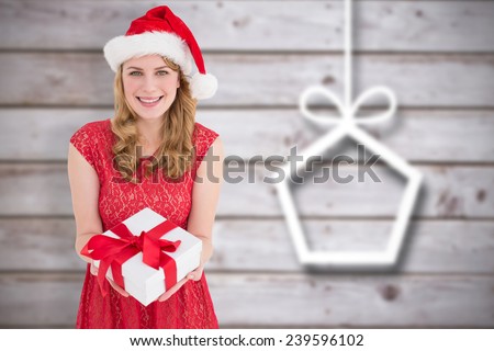Smiling pretty woman in red dress offering present against blurred christmas decorations on wood