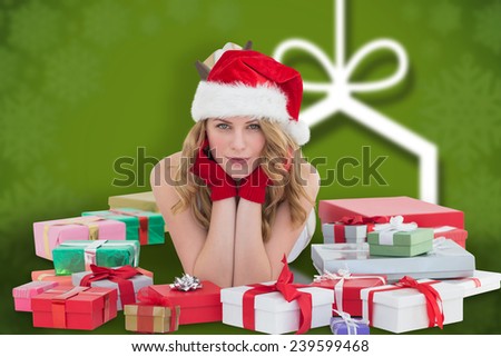 Woman in santa hat laying on the floor with gifts around her against blurred christmas background