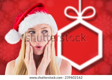 Festive blonde looking surprised with hands on face against blurred christmas background