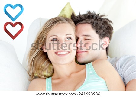 Portrait of a hugging couple sitting on a sofa in the livingroom against hearts