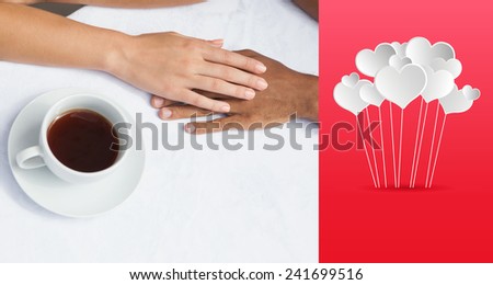 Couple having coffee together holding hands against hearts