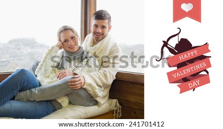 Couple in winter clothing sitting against cabin window against happy valentines day