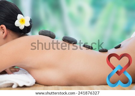 Beautiful brunette enjoying a hot stone massage against linking hearts