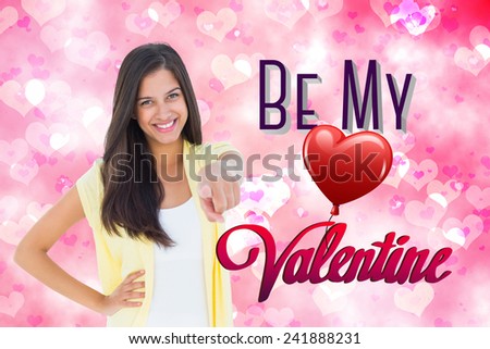 Happy casual woman pointing to camera against digitally generated girly heart design