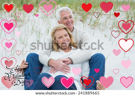 Romantic senior couple relaxing at beach against happy valentines day