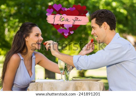Couple feeding strawberries to each other at outdoor cafÃ?Â© against i love you