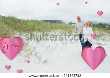 Cheerful senior couple walking at beach against valentines love hearts