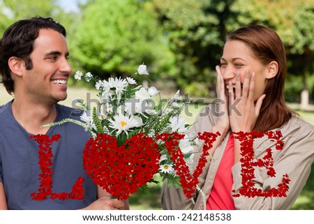 Young woman holding her hands against her face when presented with flowers against love spelled out in petals
