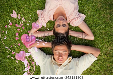 Woman and a man lying head to head with both hands behind their neck against valentines heart design