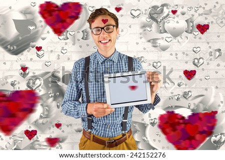 Geeky businessman showing his tablet pc against grey valentines heart pattern