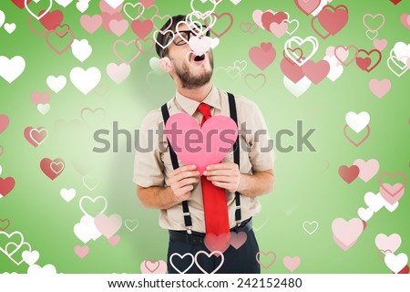 Geeky hipster crying and holding heart card against green vignette