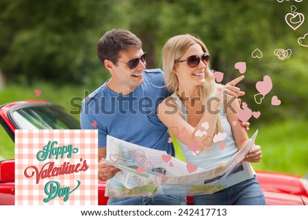 Cheerful young couple reading map against happy valentines day