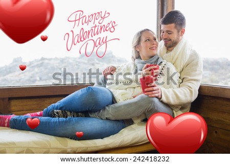 Loving couple in winter wear with cups against cabin window against happy valentines day