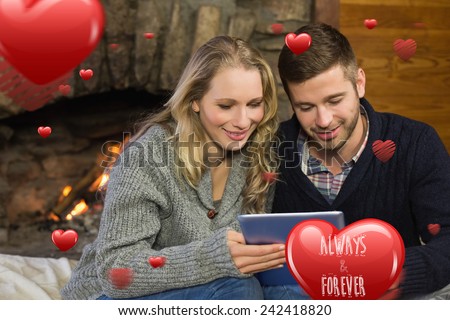 Couple using tablet PC in front of lit fireplace against always and forever