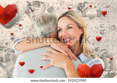 Happy couple standing and hugging against grey valentines heart pattern