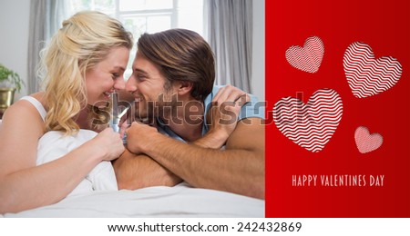 Cute couple relaxing on bed smiling at each other against cute valentines message