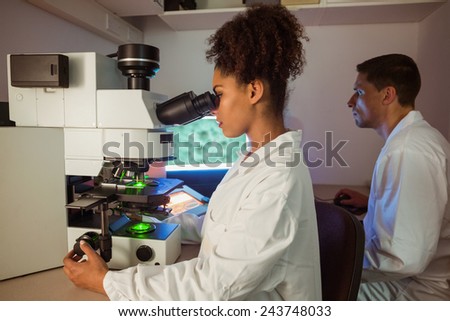 Science students working in the laboratory one looking through microscope at the university