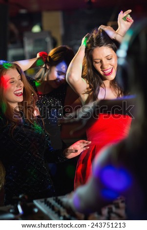Happy friends dancing by the dj booth at the nightclub