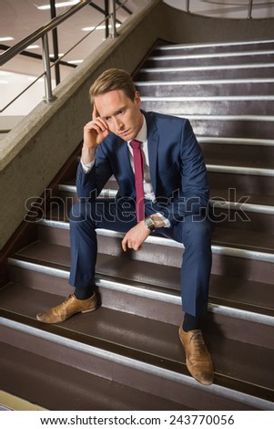 Stressed businessman sitting on steps in office building