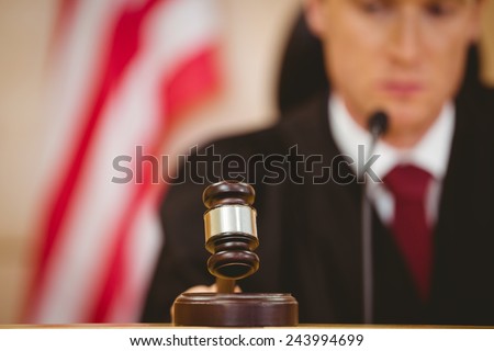 Stern judge about to bang gavel on sounding block in the court room