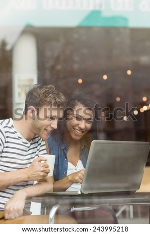Smiling friends with a hot drink using laptop in cafe at the university