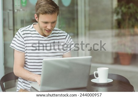 Smiling student using laptop in cafe at the university