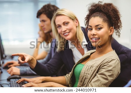 Cheerful teacher and student looking at camera in the computer room