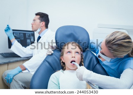 Female dentist examining girls teeth in the dentists chair