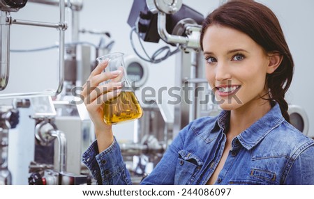 Smiling woman holding a beaker of beer in the factory