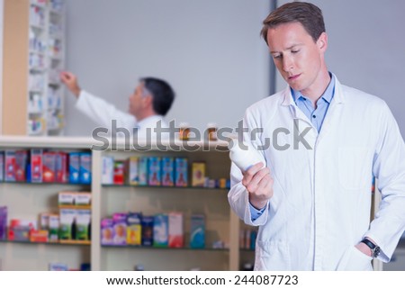 Concentrating pharmacist reading label on medicine jar in the pharmacy