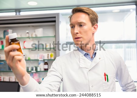 Handsome pharmacist holding medicine jar at the hospital pharmacy