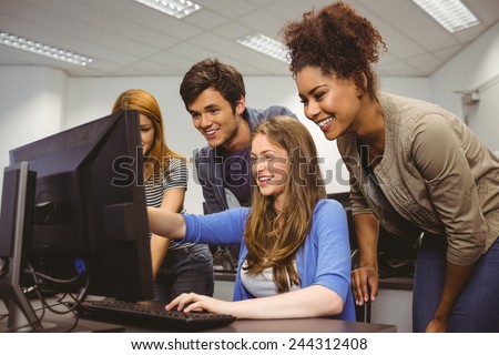 Cheerful student pointing at computer in computer room